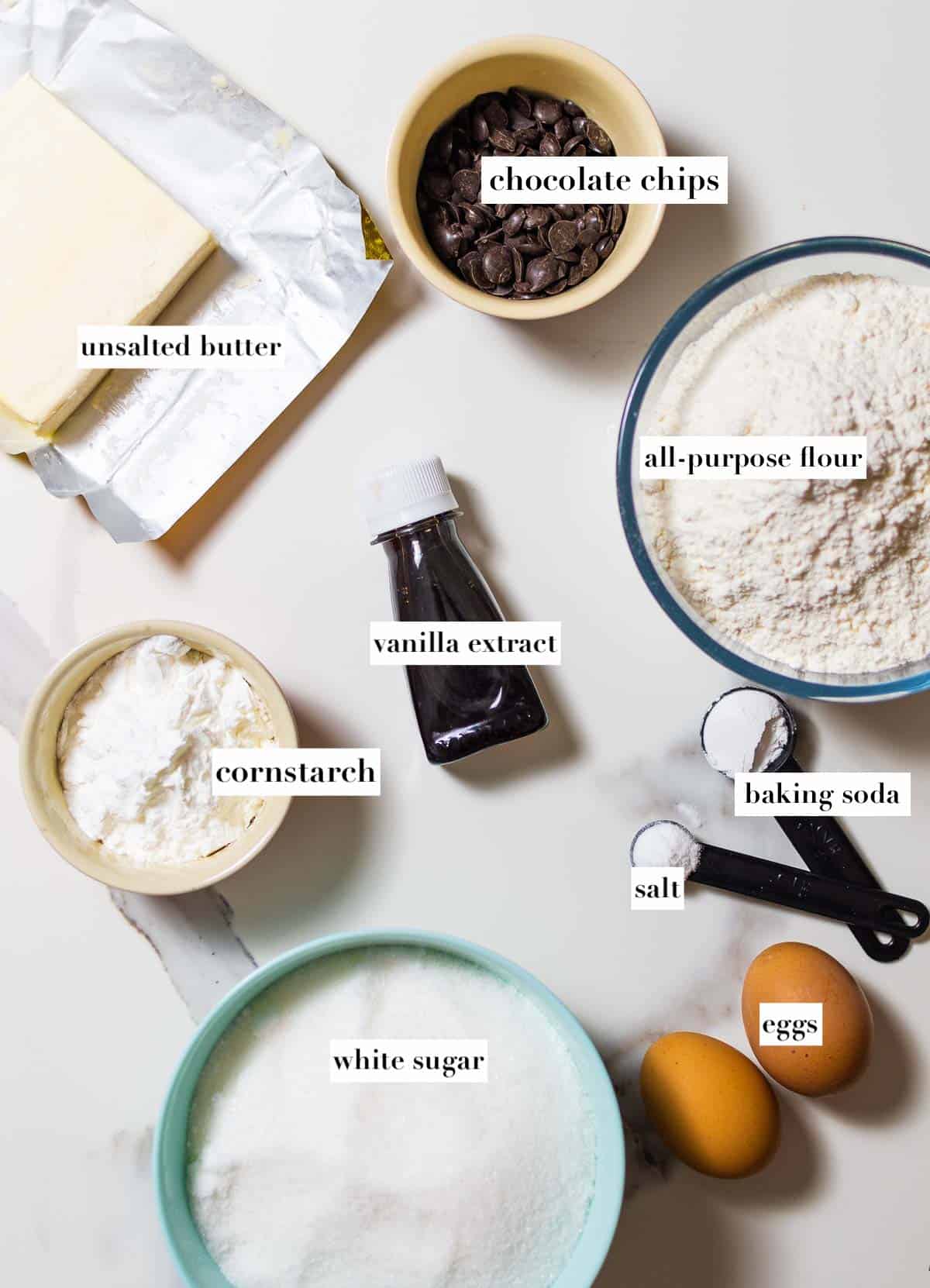 list of ingredients in bowls including block of butter, chocolate chips, cornstarch, flour, vanilla extract, and sugar