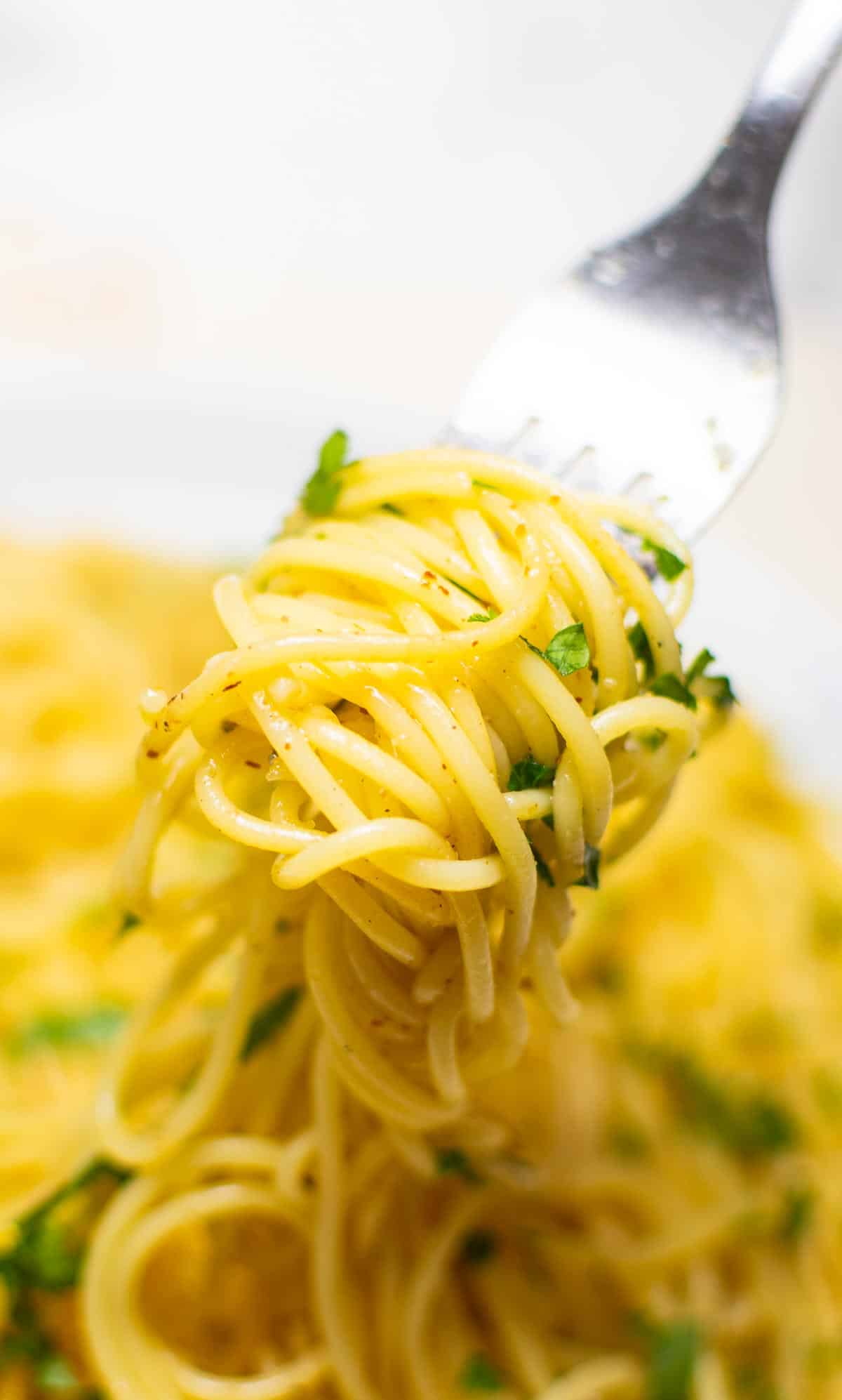 Lemon garlic spaghetti with parmesan on a large white plate and a fork.
