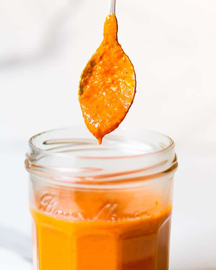 Dipping a spoon in homemade buffalo sauce.