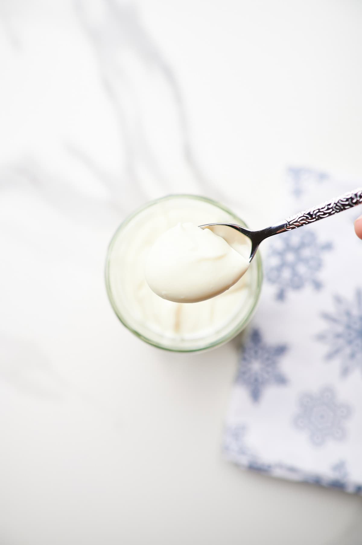 spoon full of homemade mayonnaise with an egg in the background