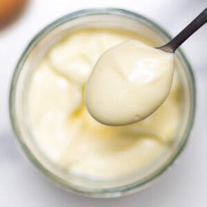 close-up homemade mayonnaise in a glass jar with en egg in background