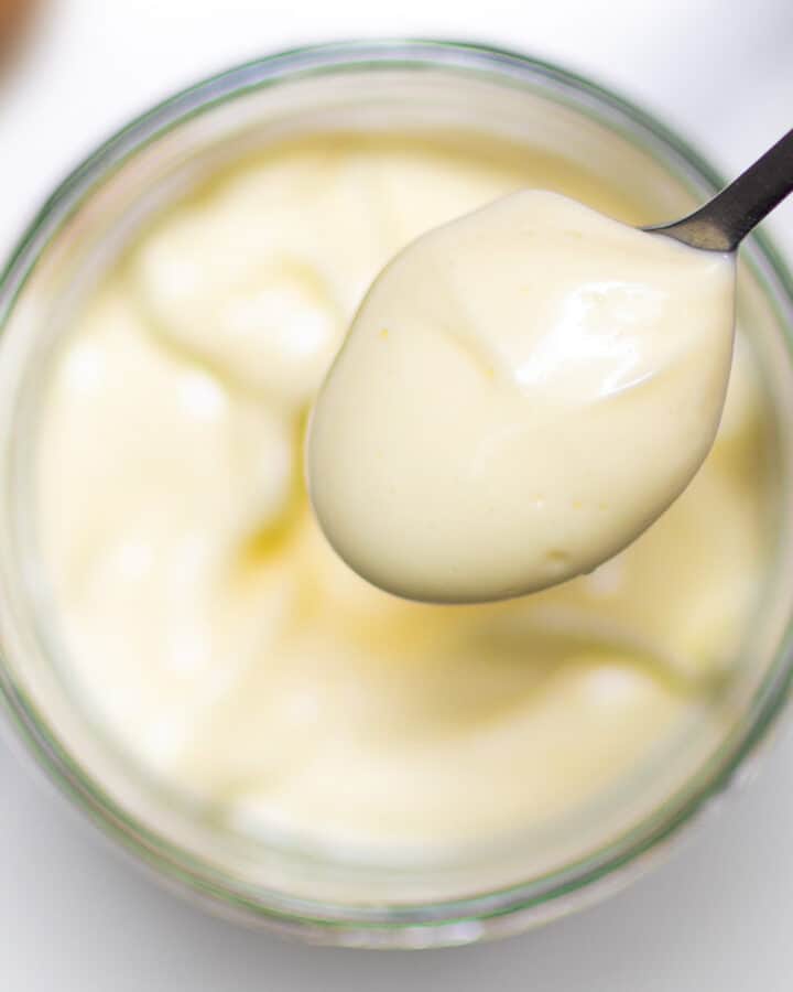 close-up homemade mayonnaise in a glass jar with en egg in background