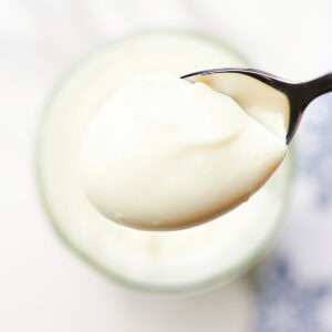 close-up homemade mayonnaise in a glass jar with en egg in background