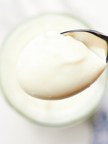 close-up homemade mayonnaise in a glass jar with en egg in background