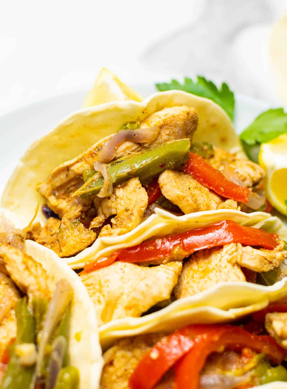 close-up chicken fajitas with red peppers on white surface