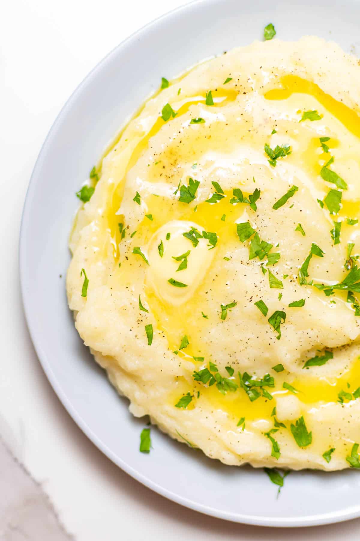 overlay shot of garlic mashed potatoes with melted butter and parsley on top