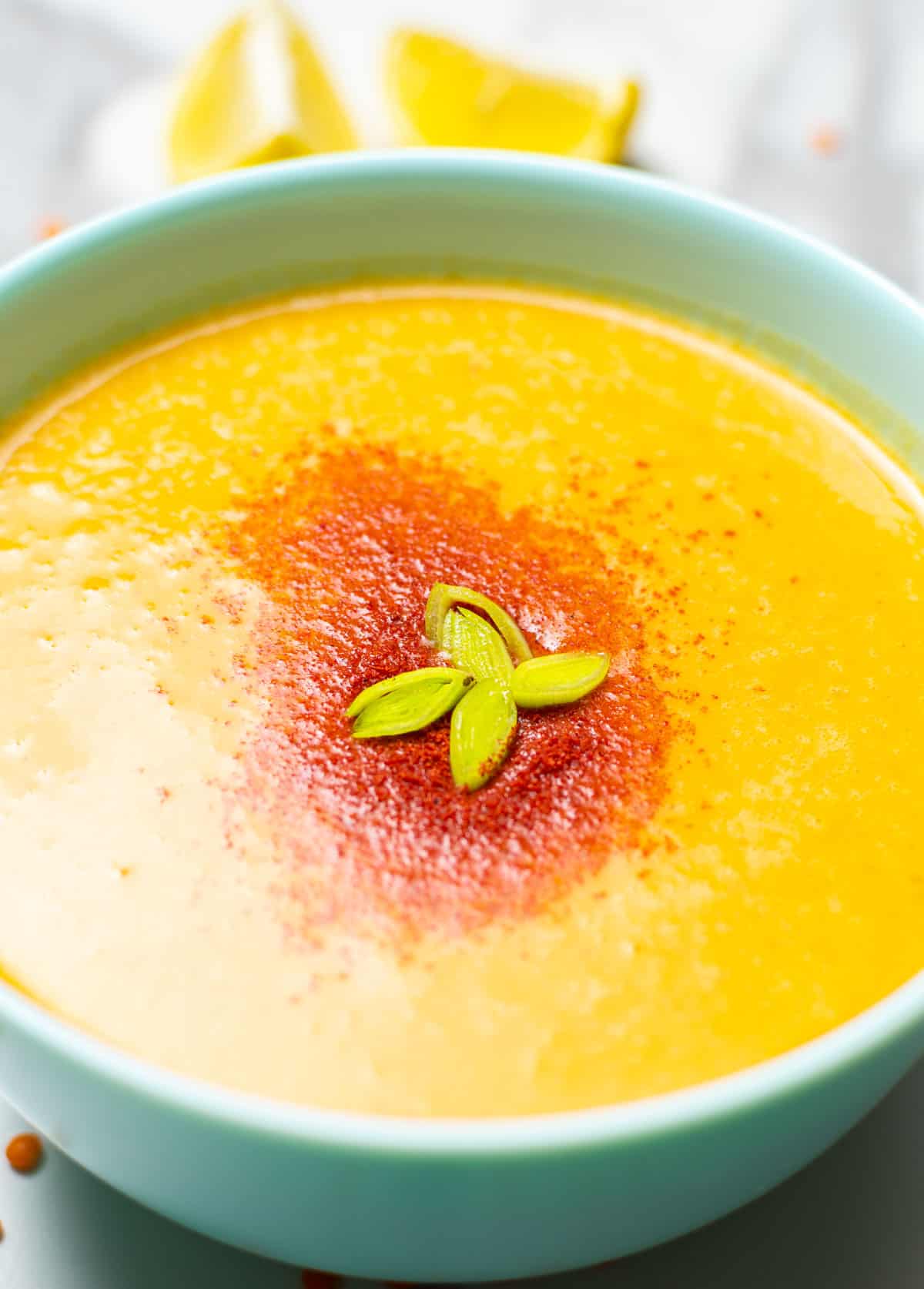 close-up of red lentil soup with slice of lemon in the background