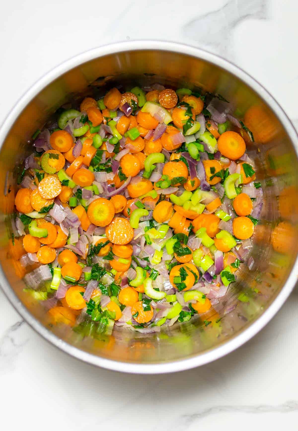 Chopped carrots and celery stirred in a saucepan.
