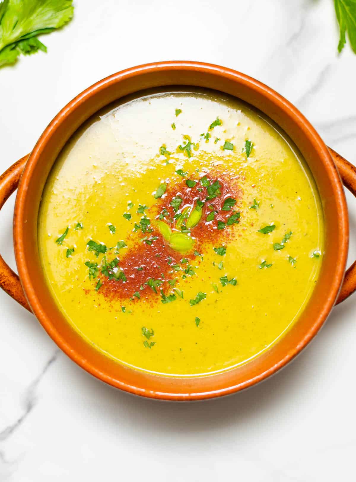 carrot and celery soup on stone pot overlay view