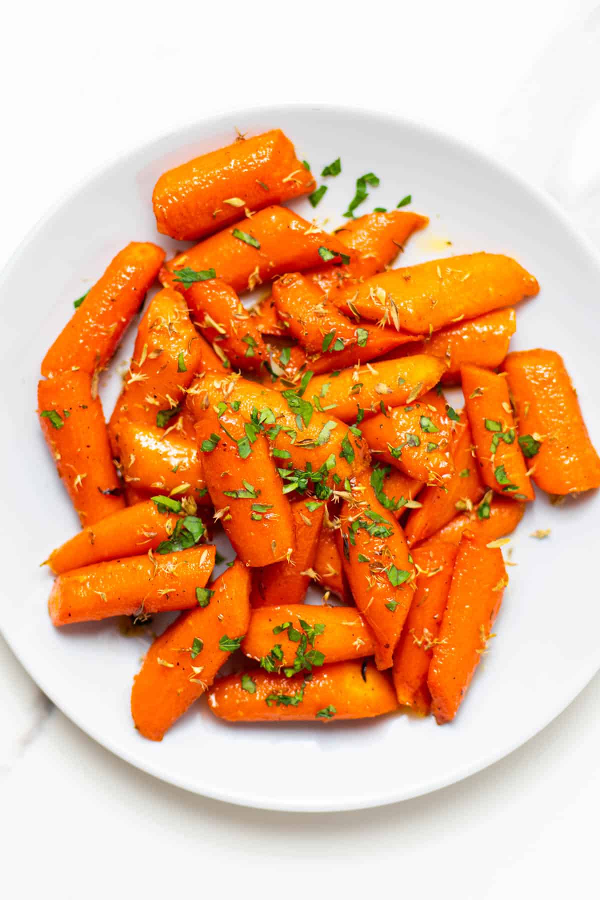 cooked brown sugar honey glazed carrots with parsley on top.