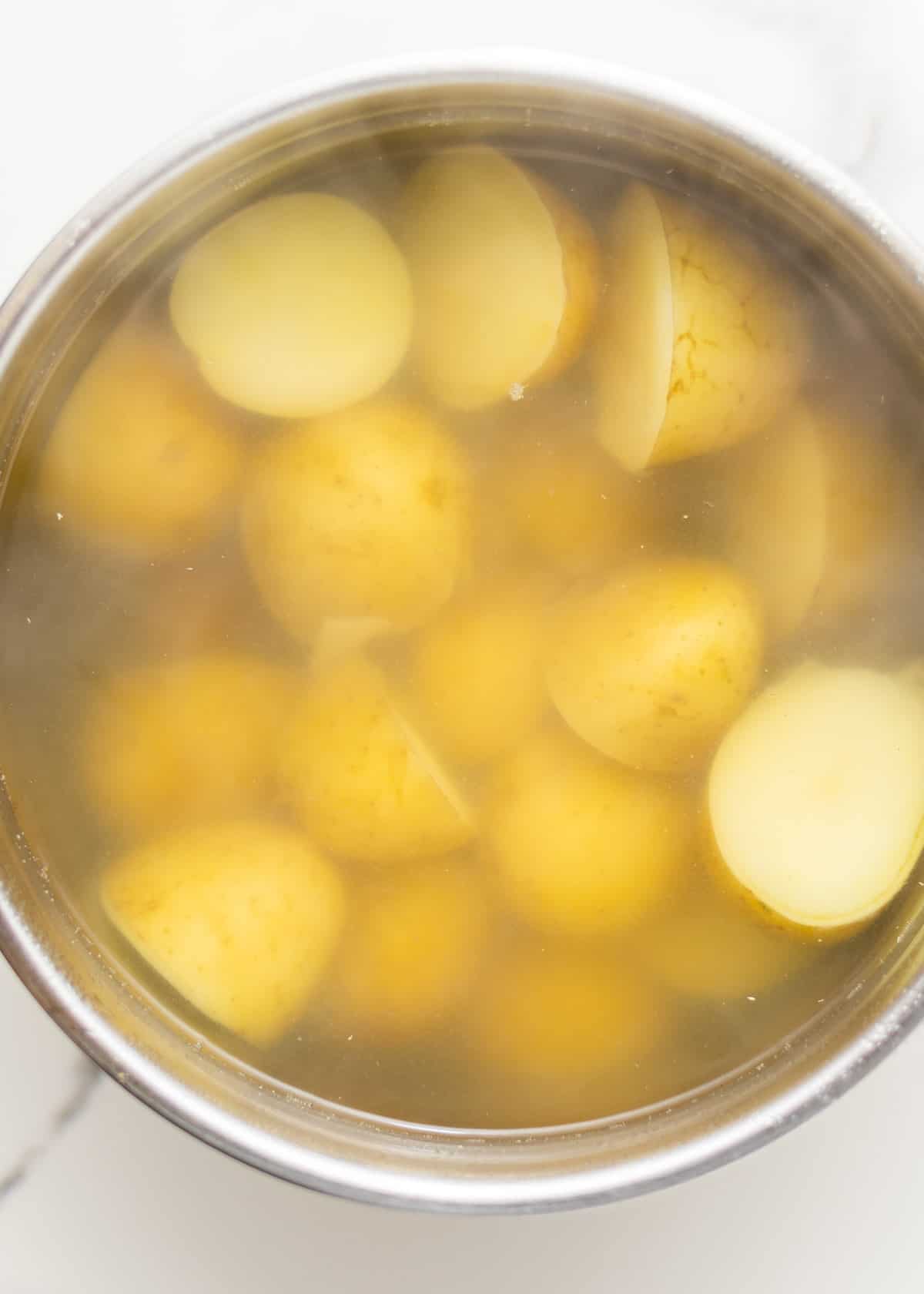 yukon gold potatoes cut in half and boiling in hot water.