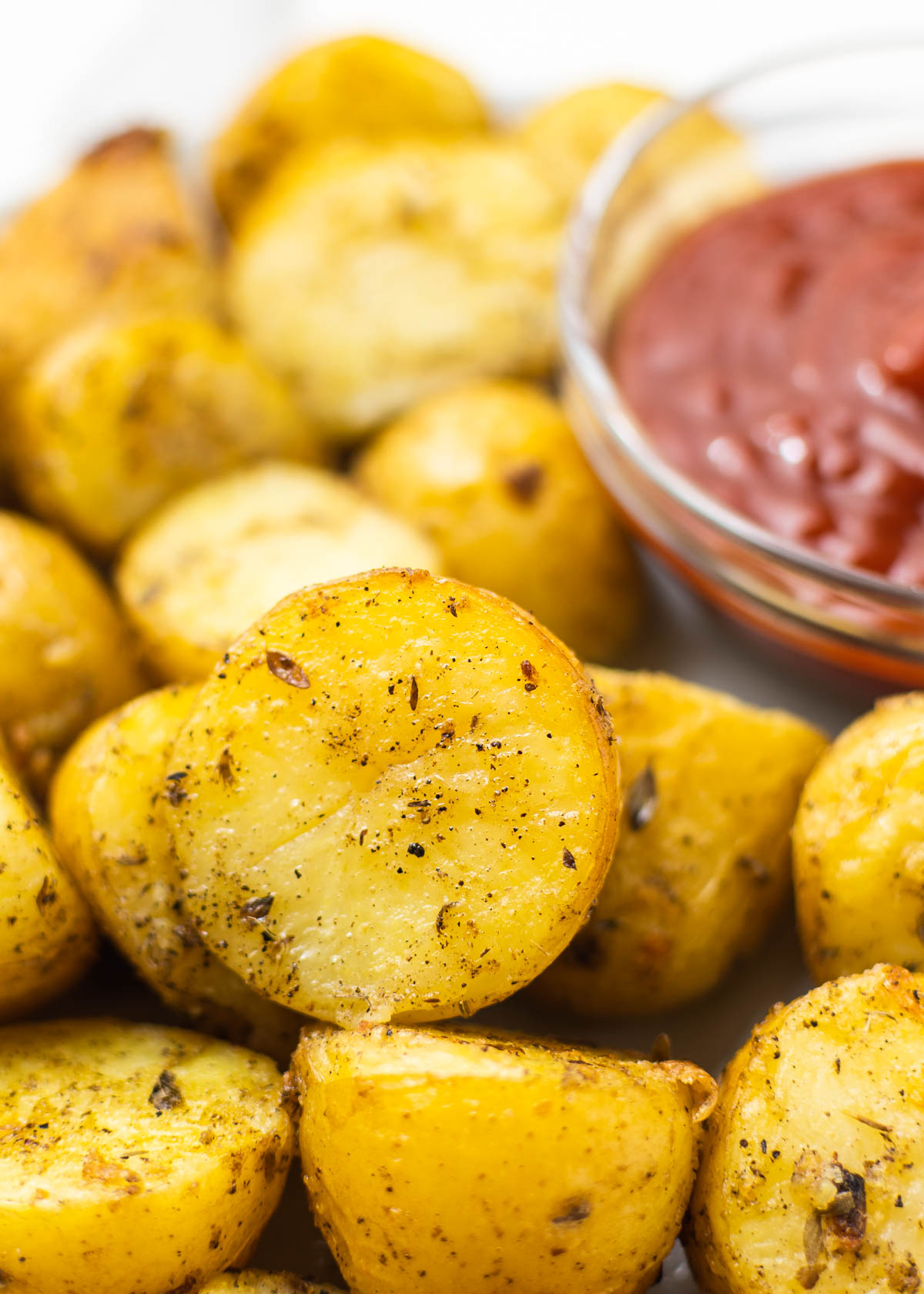 close-up shot of roasted yukon gold potatoes with ketchup on the side.