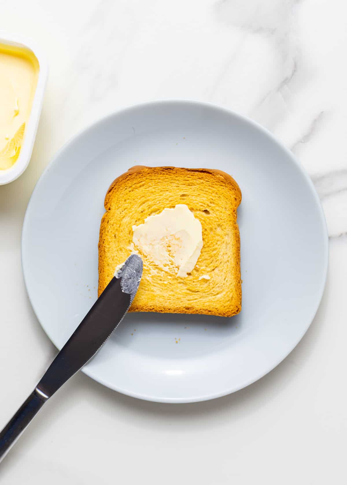 bread with butter on top on a grey dish.