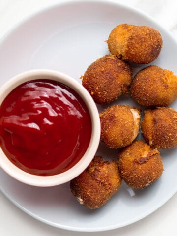 chili cheese nuggets on a plate with ketchup on the side