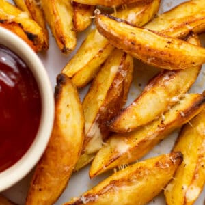 close-up overlay shot of air fried potato wedges with cheese on top and ketchup sauce on the side
