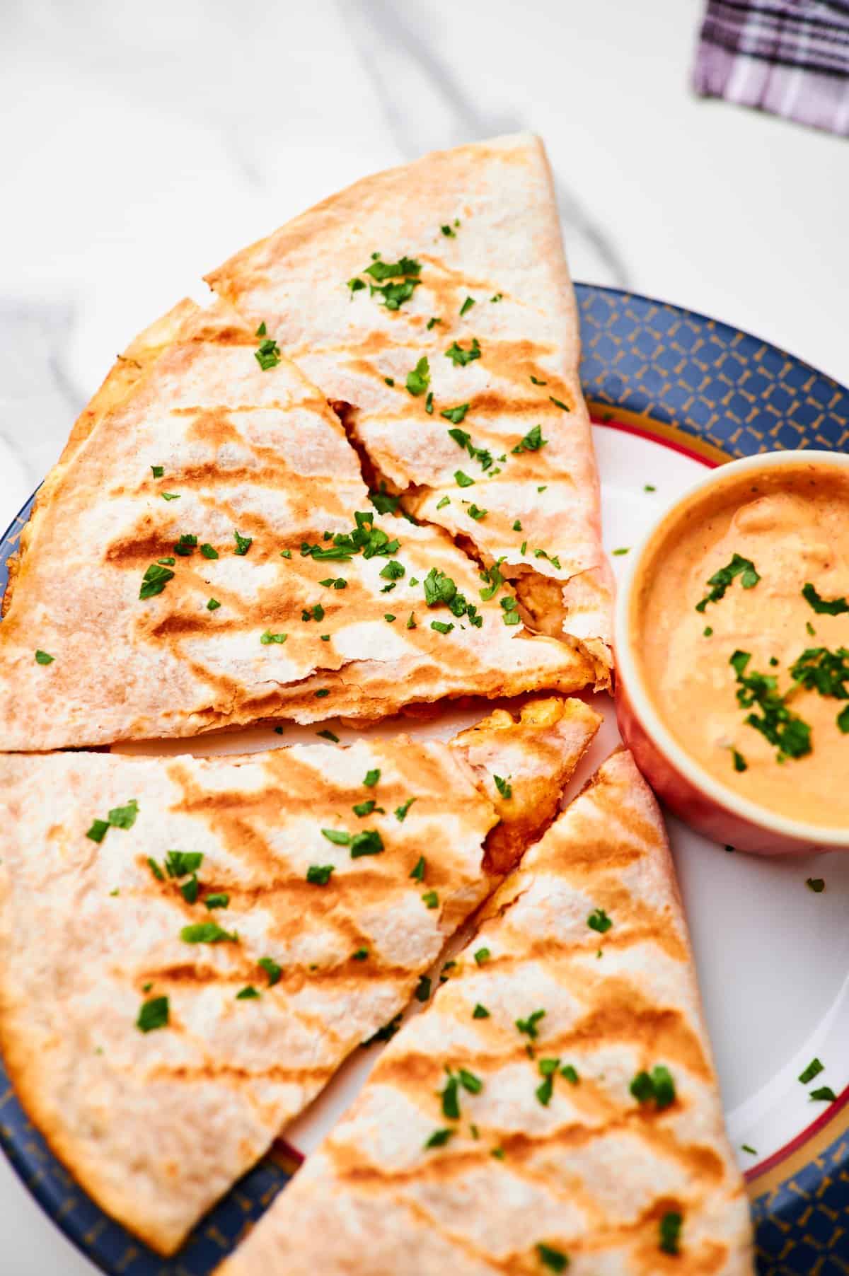 Copycat Taco Bell chicken quesadilla on  a plate with a small bowl of quesasdilla sauce.