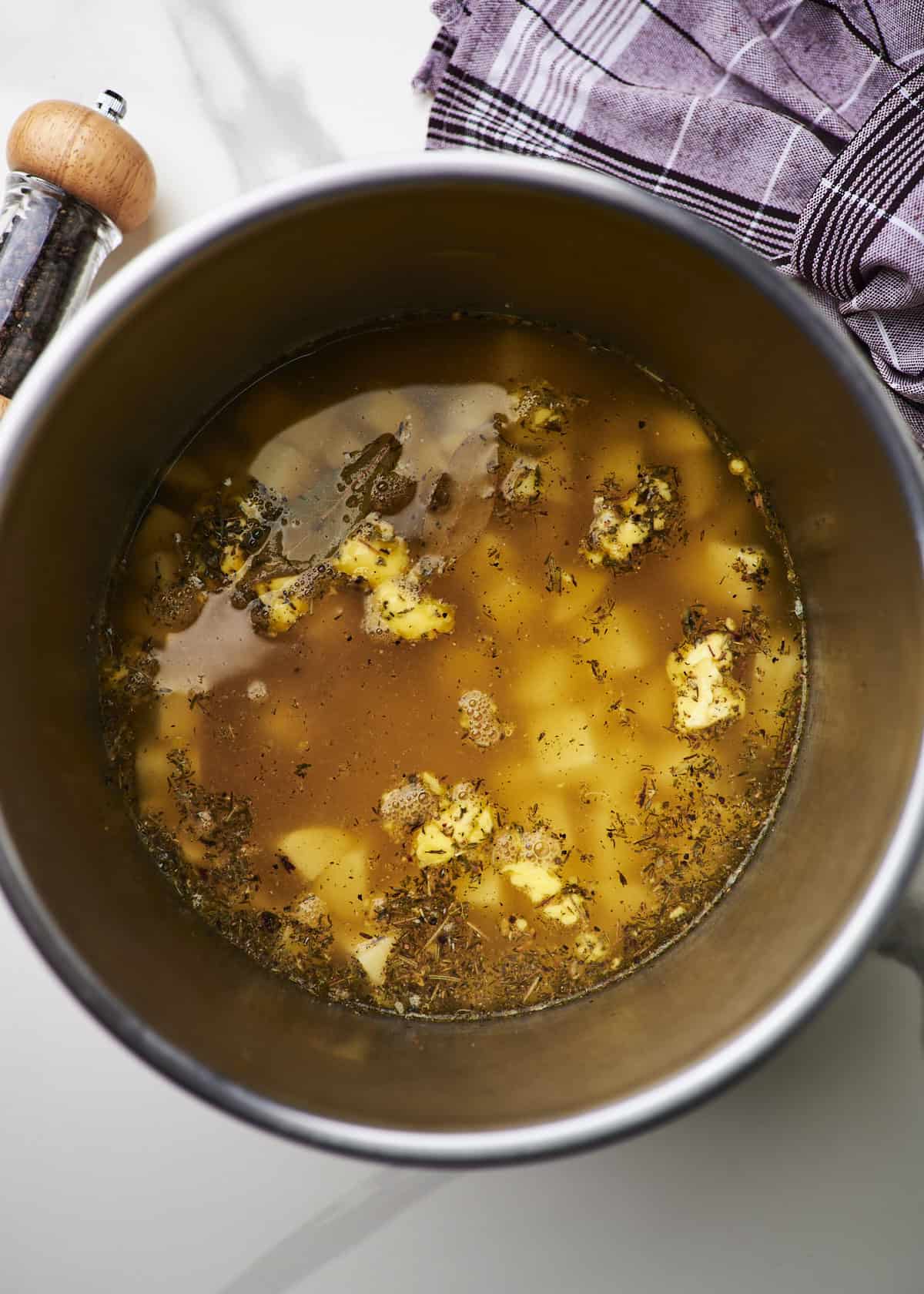 Instant pot insert filled with ingredients to make homemade creamy potato soup.