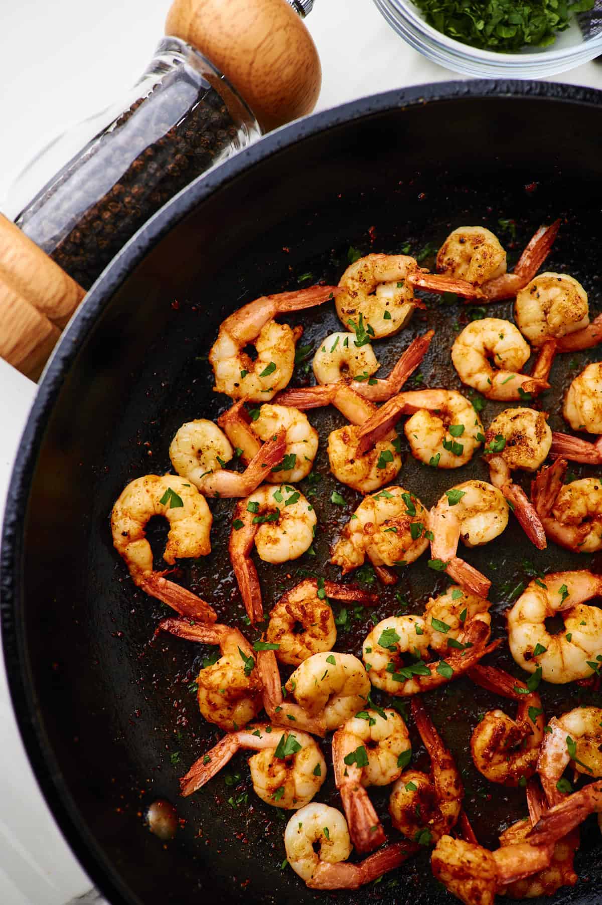 pan seared shrimp on a white plate with fresh parsley
