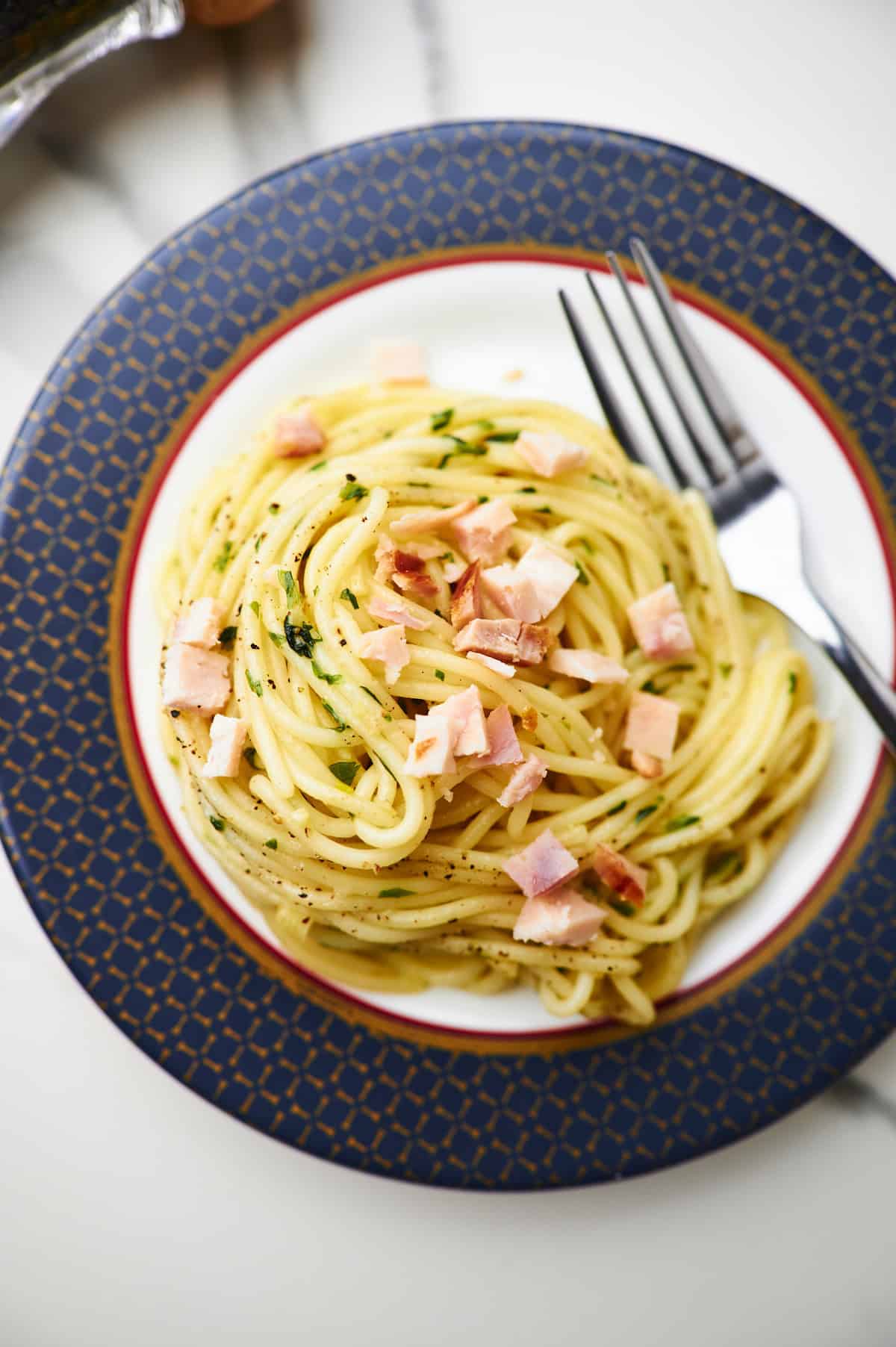 White plate filled with garlic butter sauced tossed with al dente pasta.
