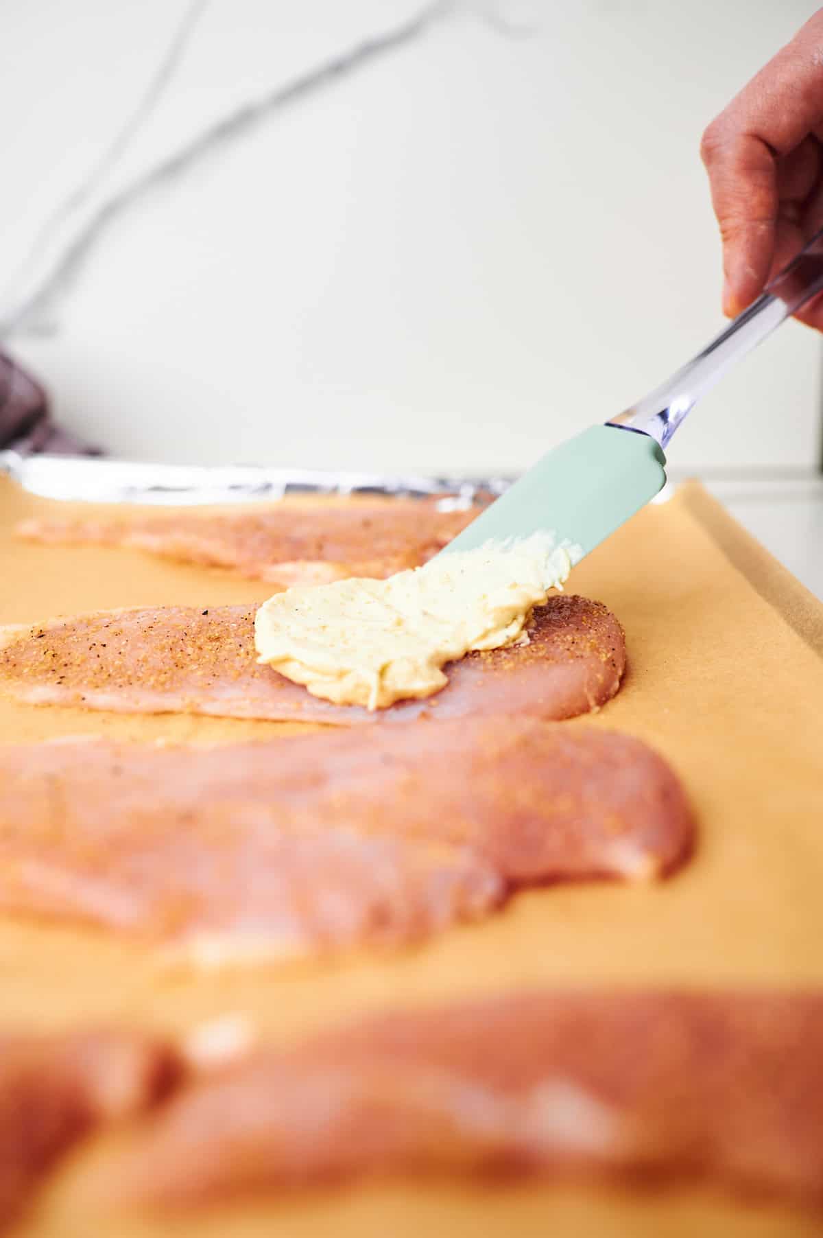 Adding Parmesan Mayo Mixture to Chicken Breasts.