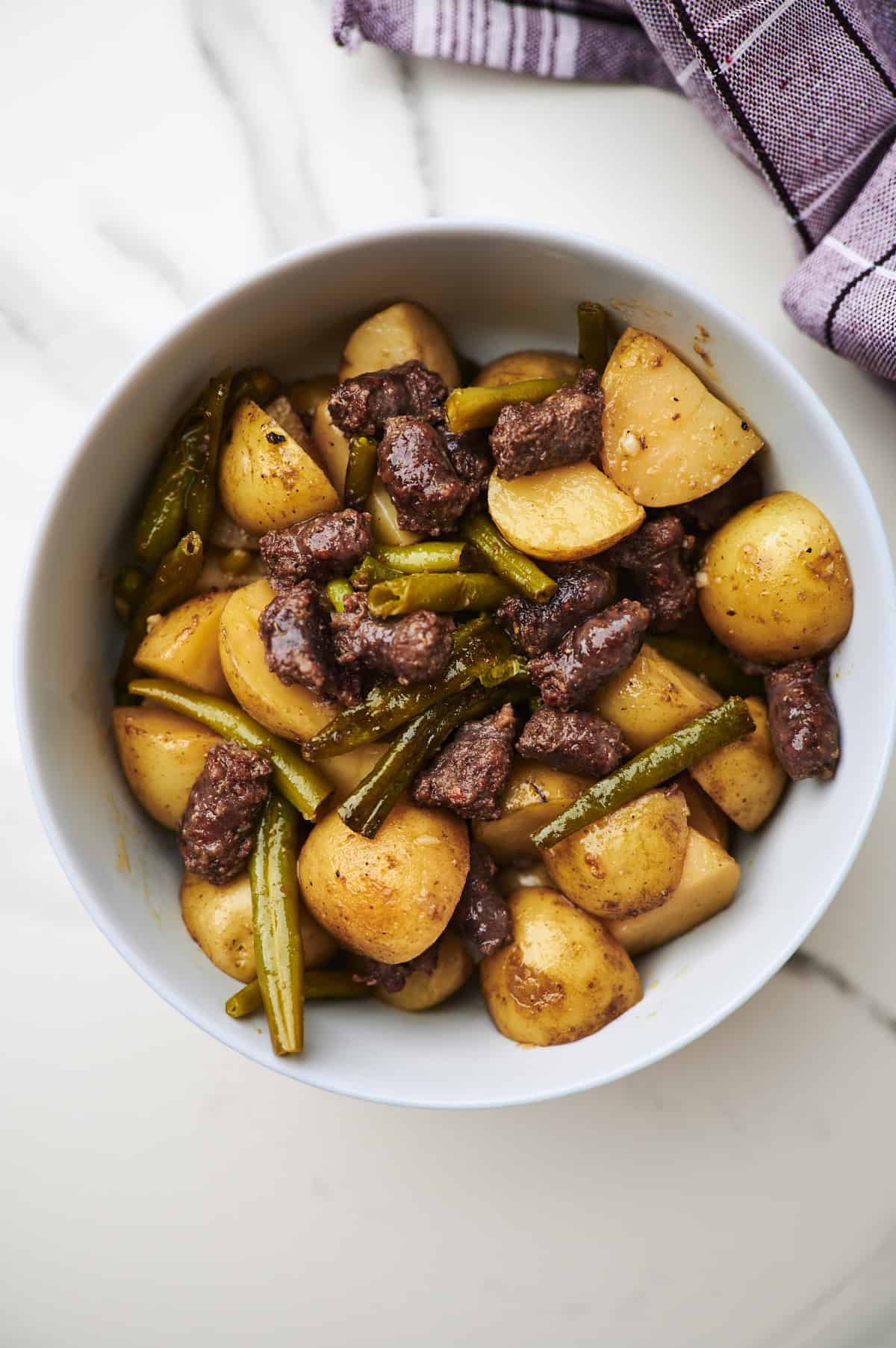 slow cooker sausage and potatoes with green beans in a grey bowl on the table