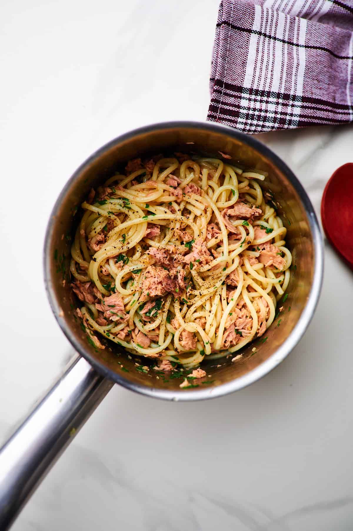 tossing pasta with tuna sauce in a saucepan next to photo of a bowl of spaghetti
