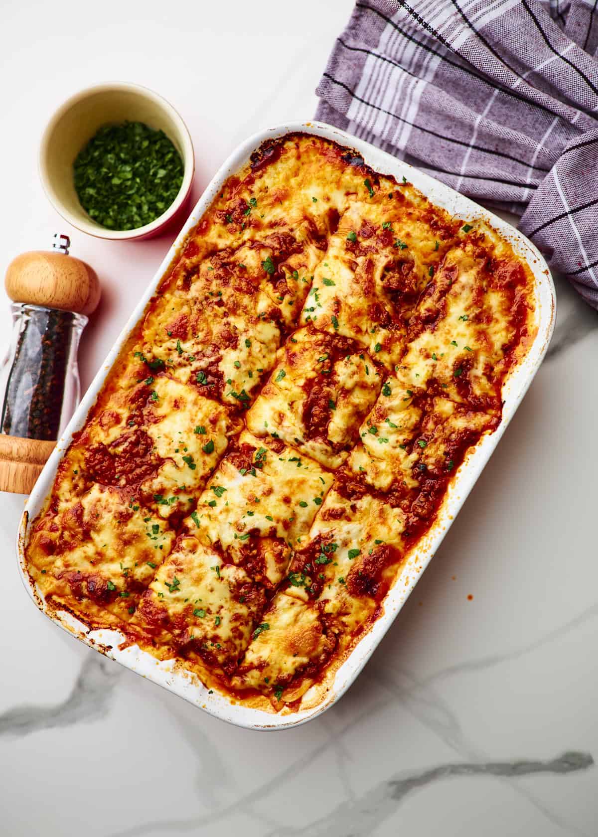 Large white baking dish filled with homemade cottage cheese lasagna garnished with parsley 