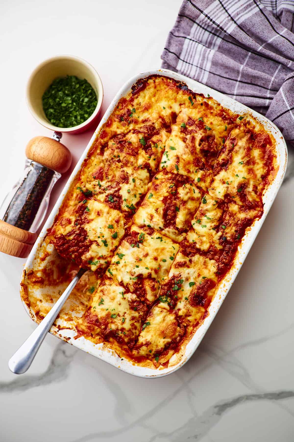 Large white baking dish filled with homemade cottage cheese lasagna garnished with parsley