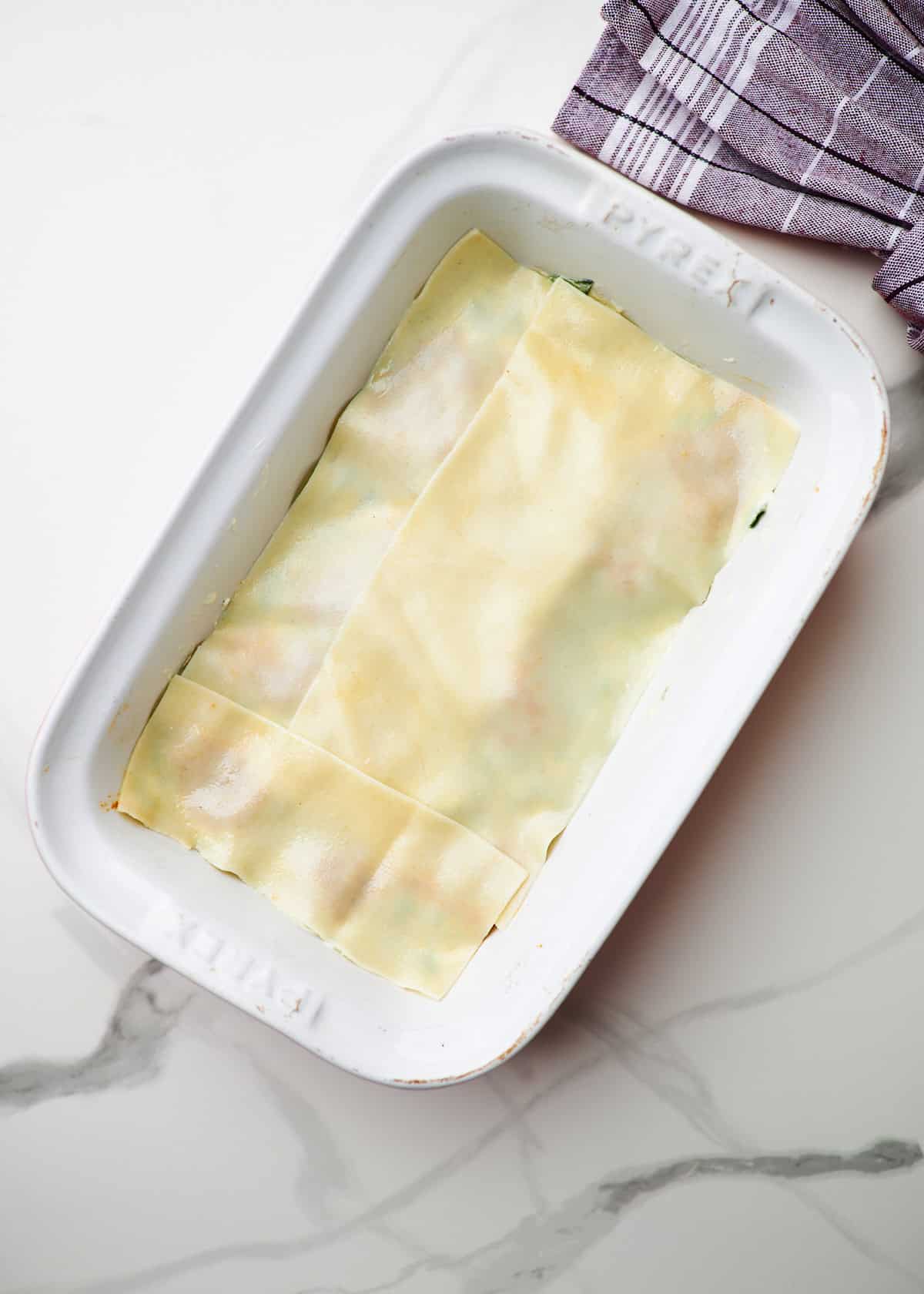 White baking dish filled with ingredients to make meaty cottage cheese lasagna
