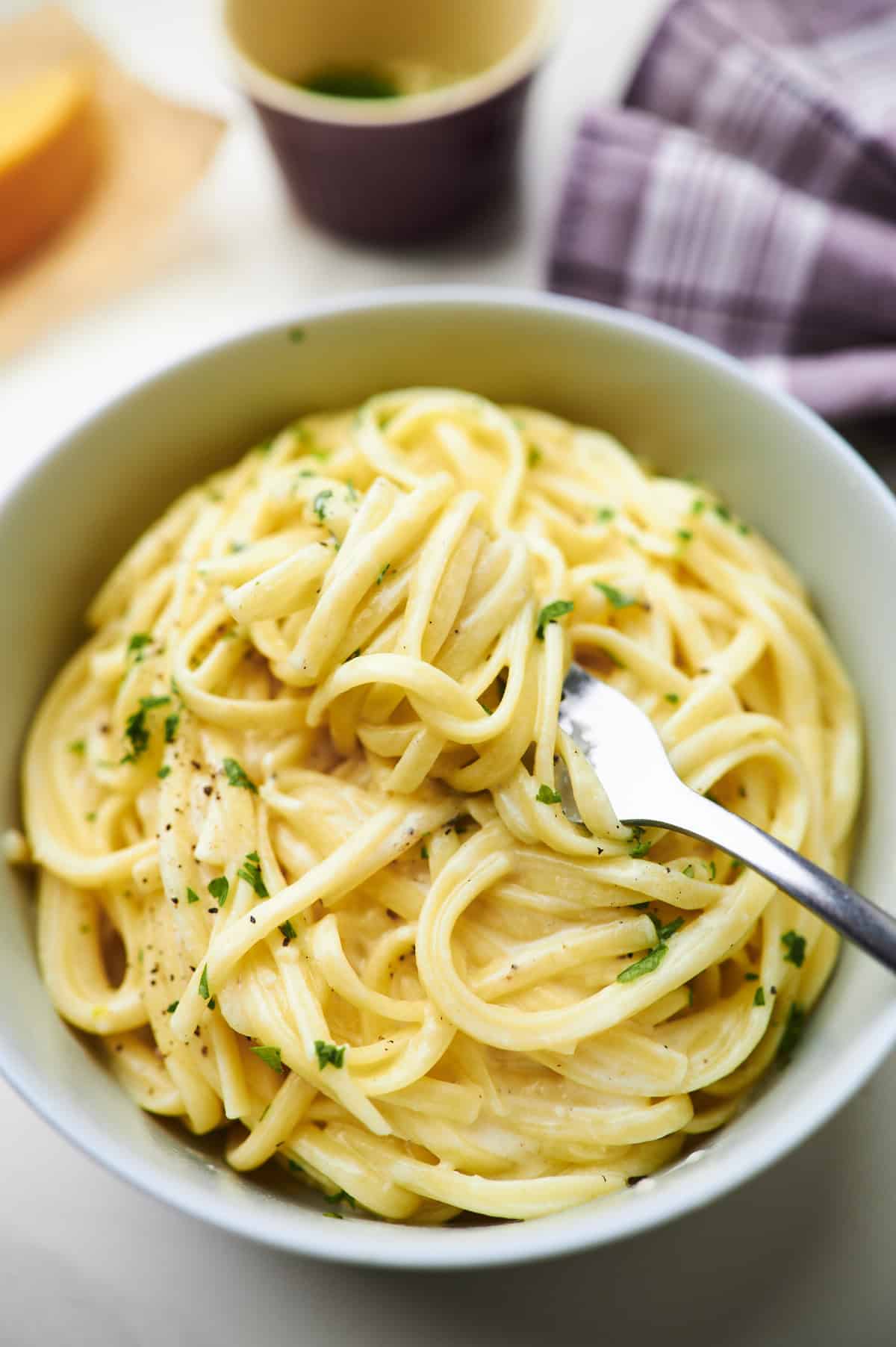 greek yogurt alfredo pasta swirled around a fork and topped with fresh parsley