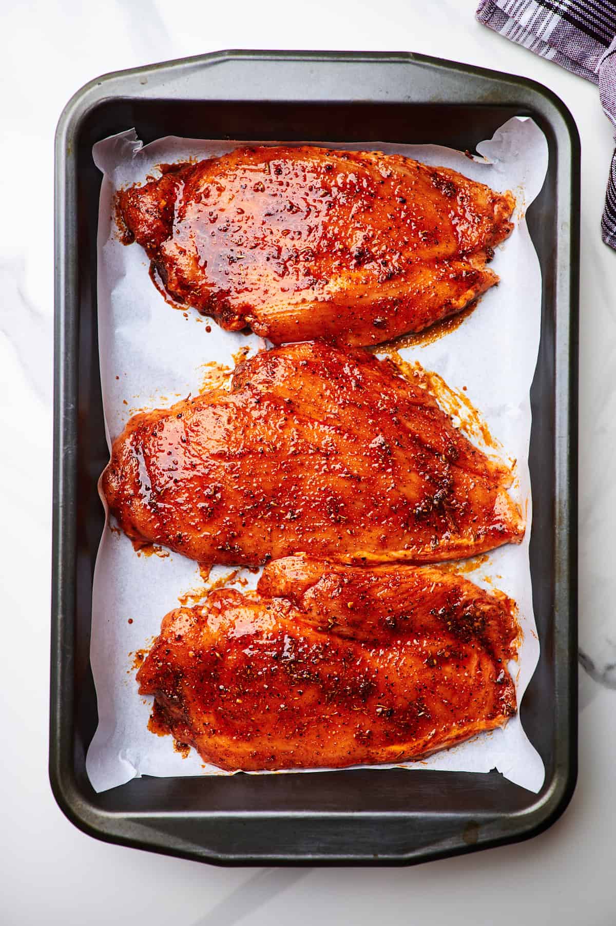 Seasoned chicken breasts in a baking dish.	