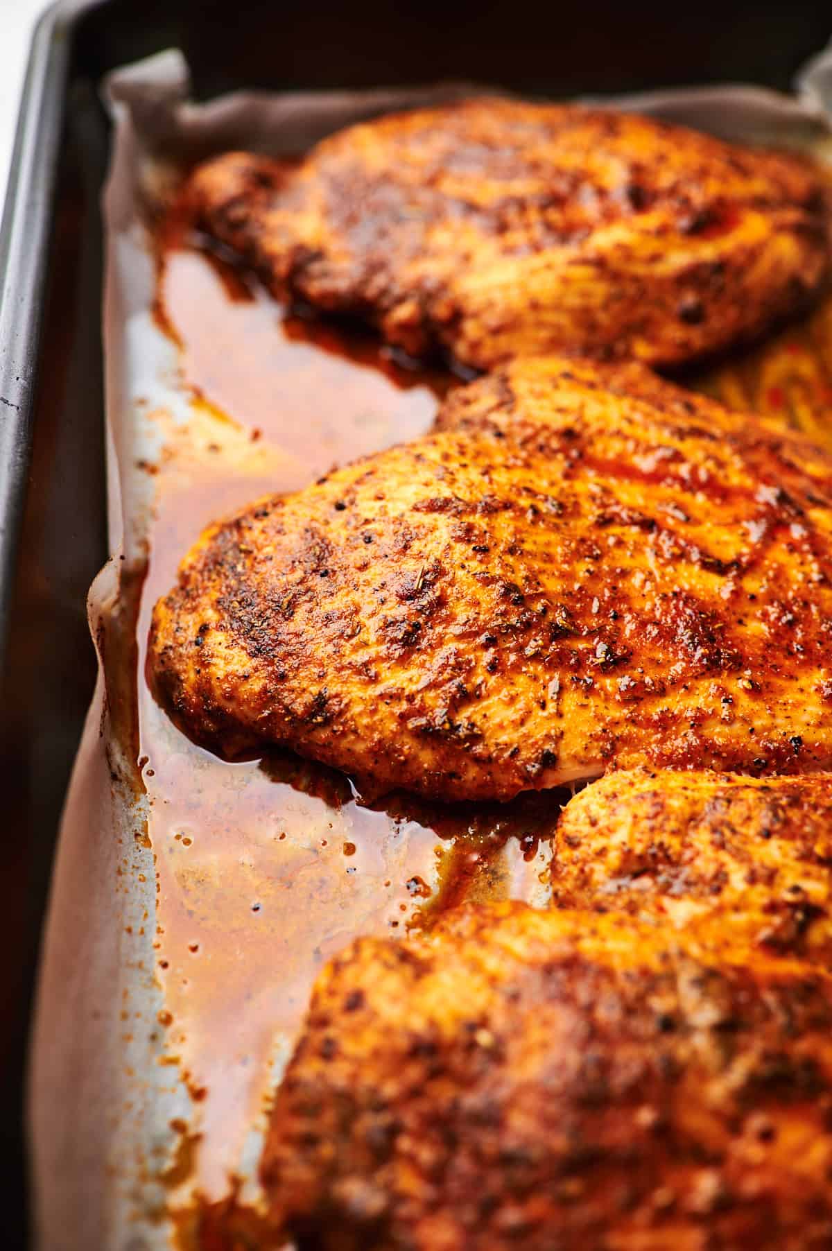 sideview of baked chicken breasts on a baking dish. 