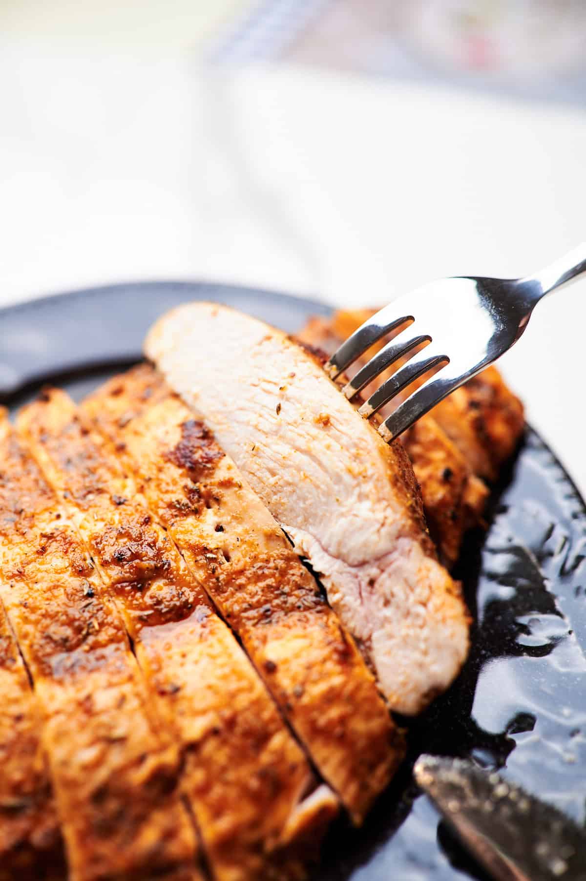 Sideview of sliced baked chicken breasts on a serving plate. 