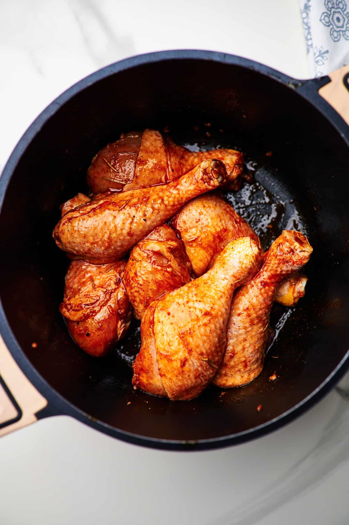 Seasoned chicken legs in a large sauce pan.