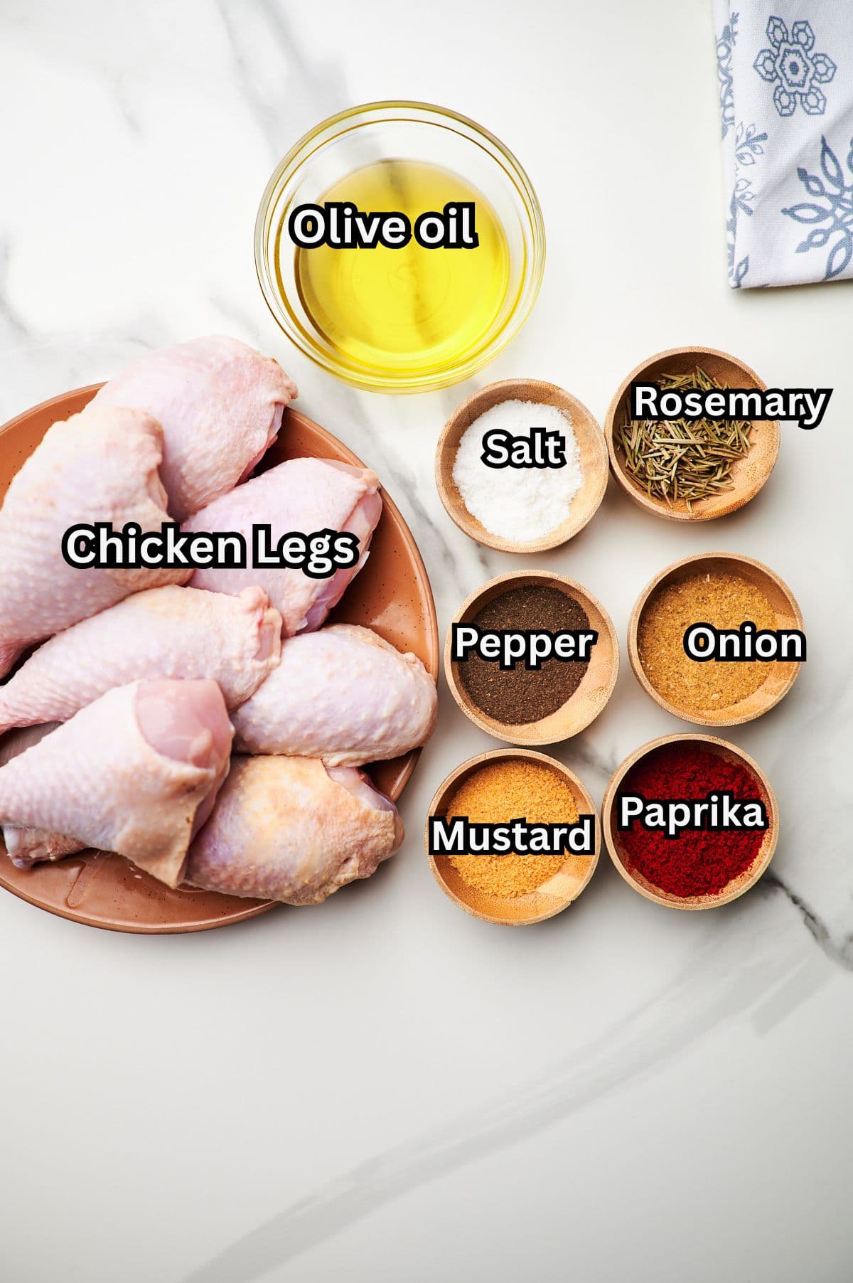 baked chicken leg ingredients spread out on a white counter.