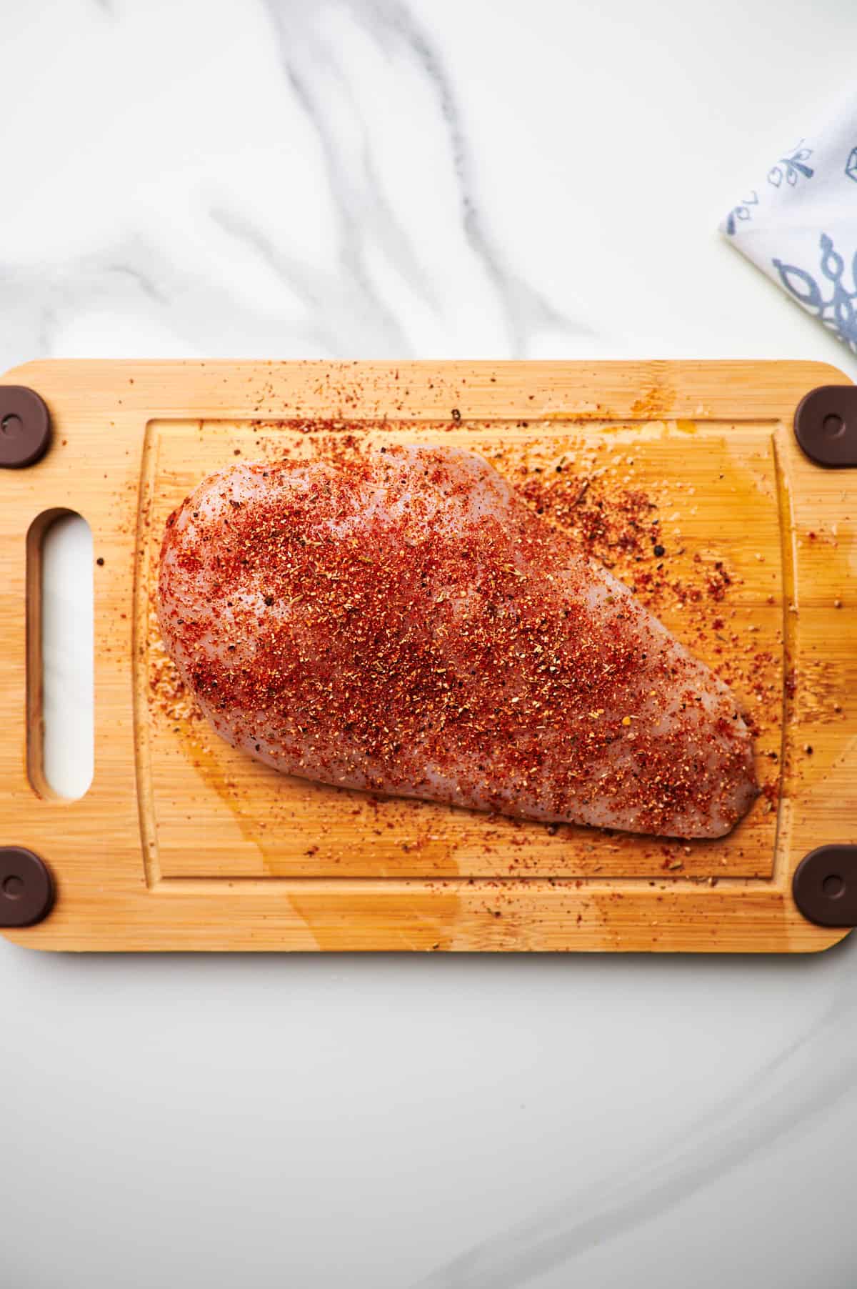 Seasoned chicken breasts on a cutting board.