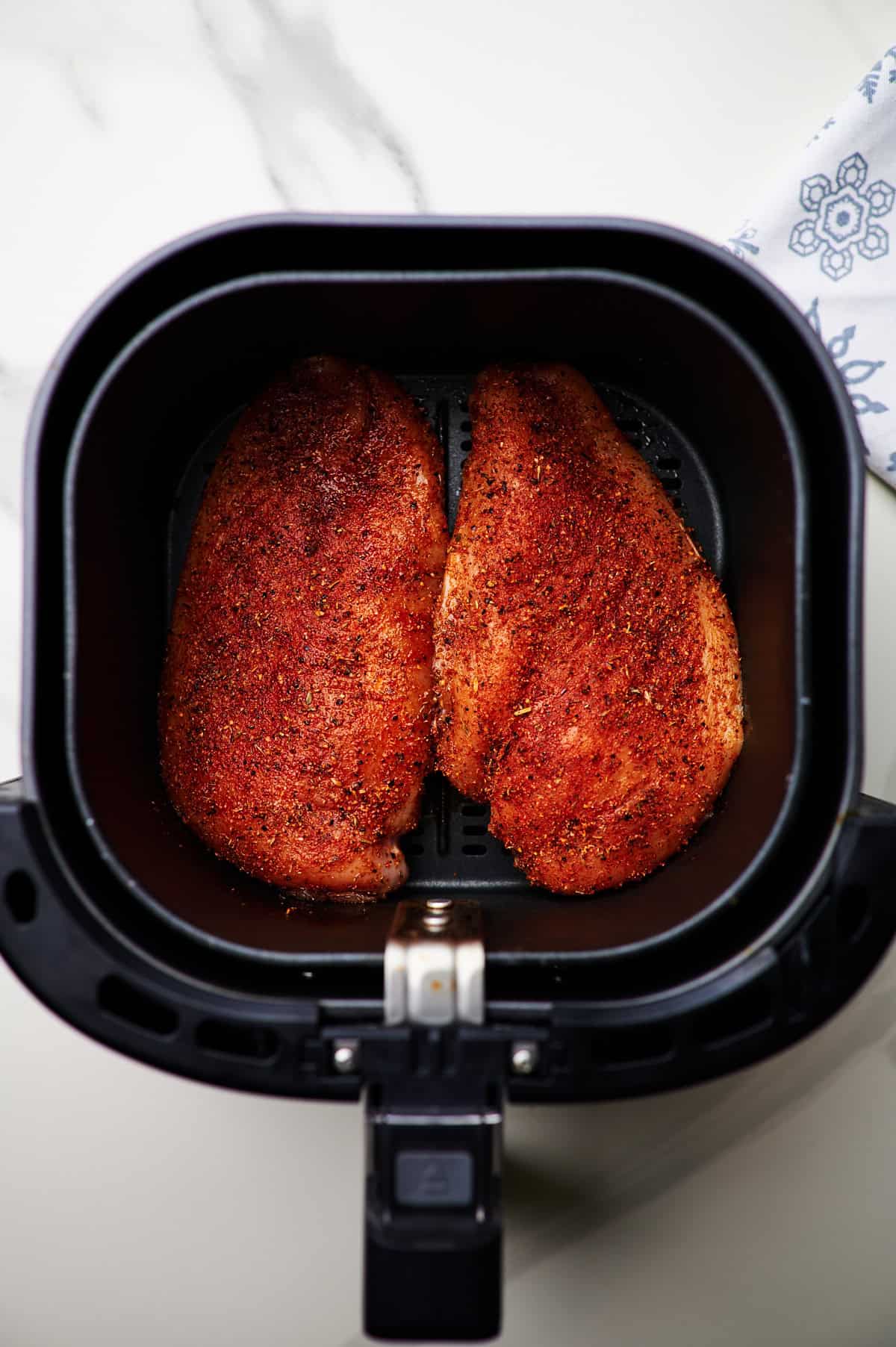 Chicken breasts added to air fryer basket.