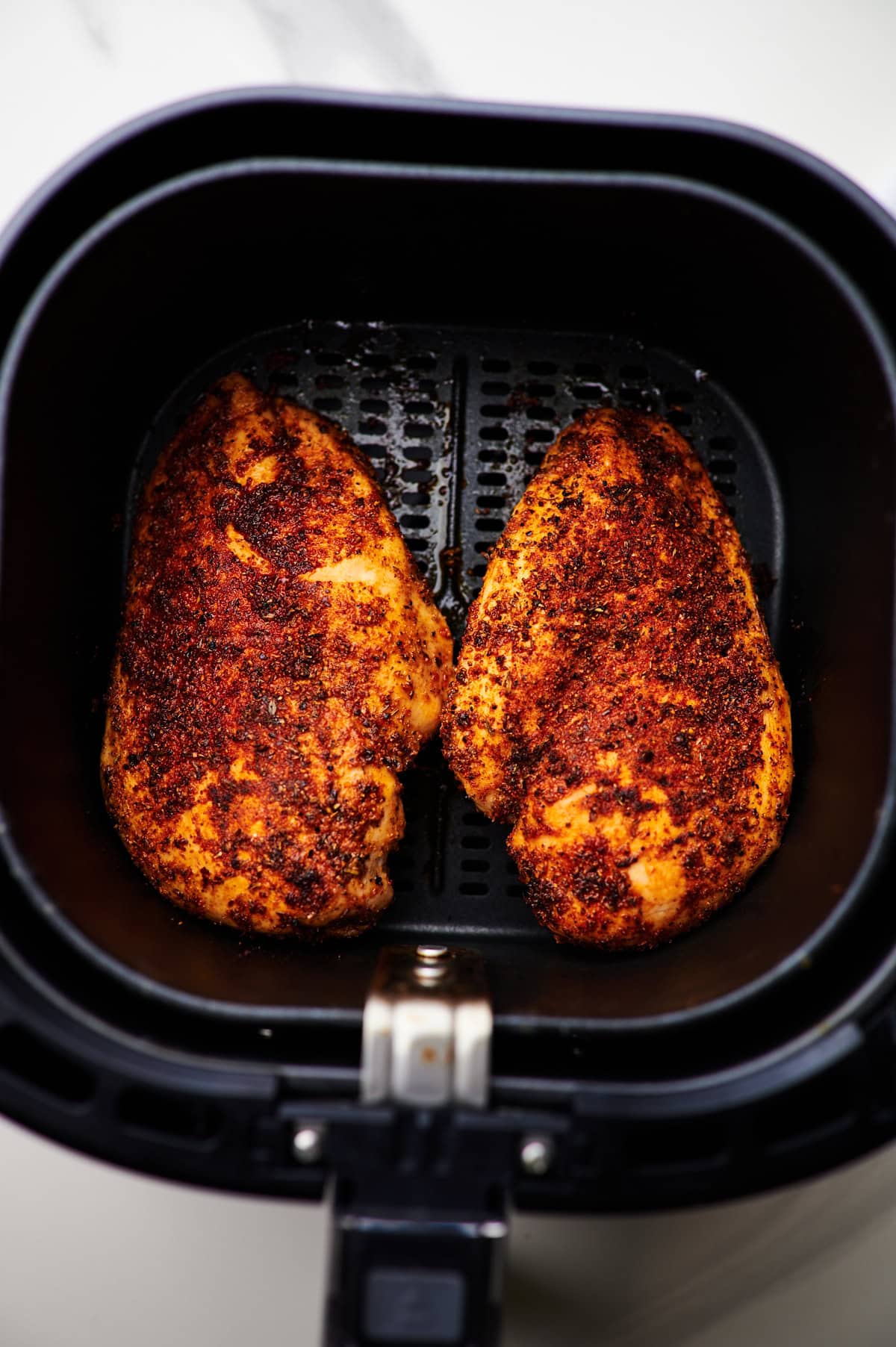baked chicken breasts in the air fryer basket.