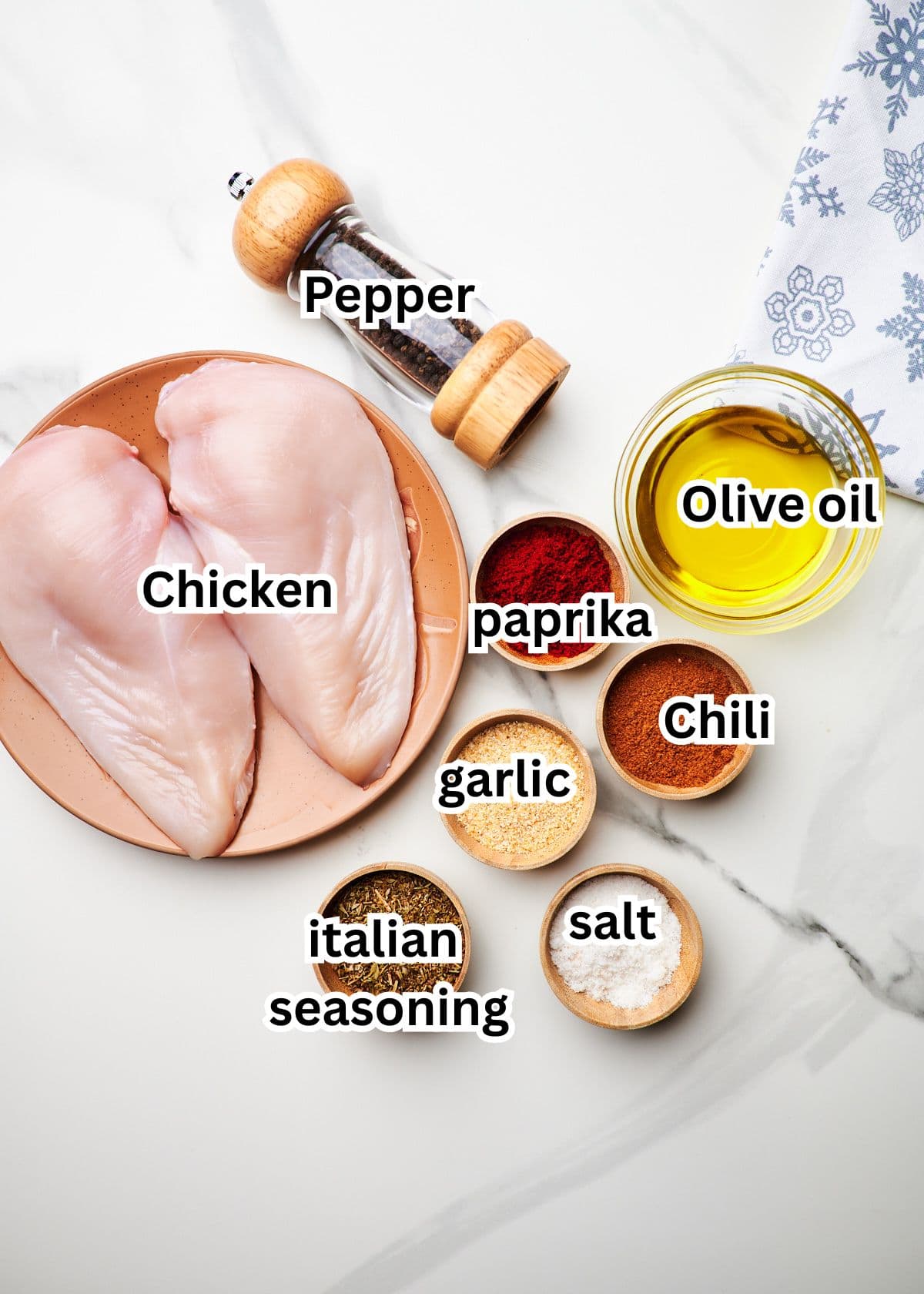 ingredients to make the air fryer chicken breast recipe over a white surface.