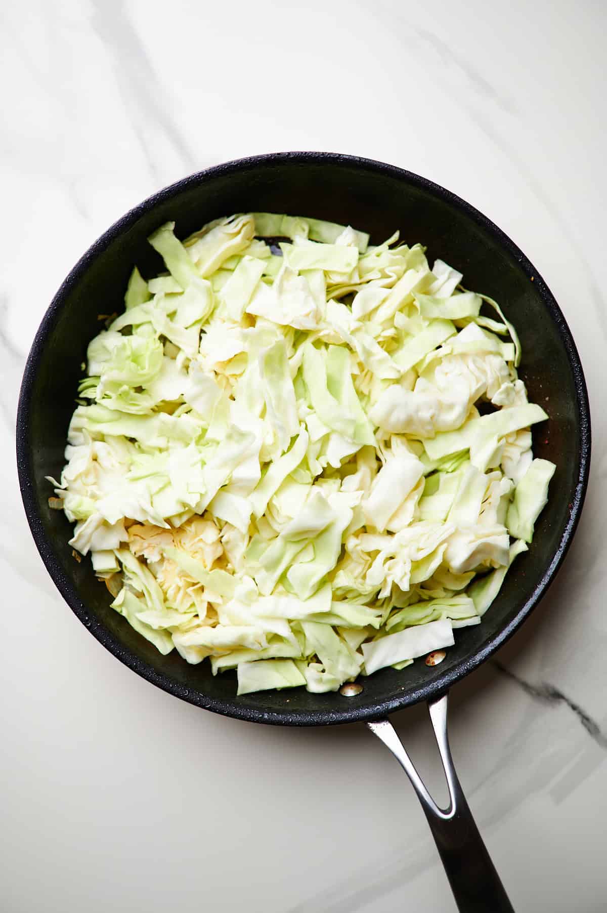 sauteing chicken in a skillet, then cooking cabbage and onions