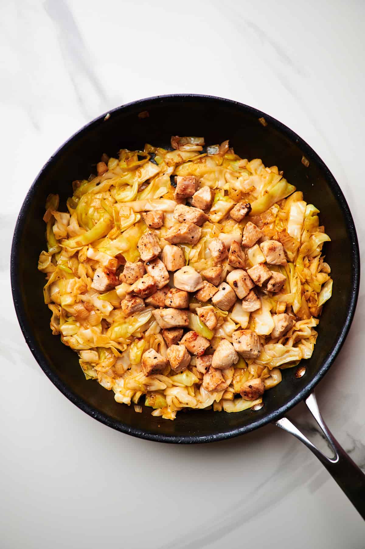 adding paprika and chicken to a skillet with sauteed cabbage